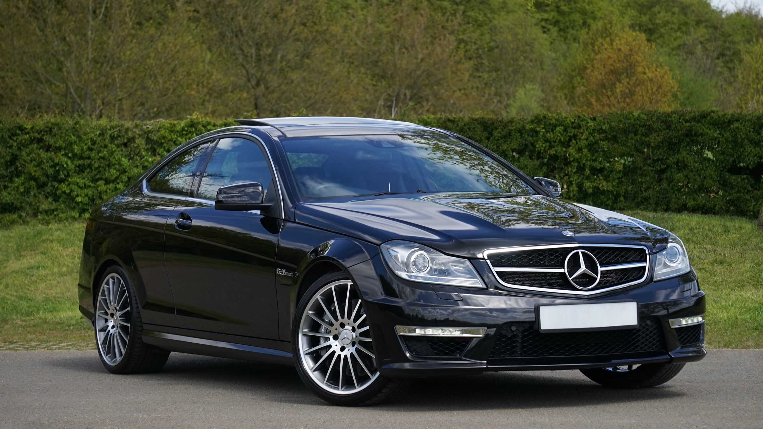 black mercedes benz driving camera right in a parl